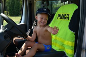 chłopczyk w policyjnej czapce siedzący za kierownicą radiowozu