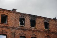 zdjęcie zrobione z perspektywy ulicy- przedstawia widok na okna spalonego piętra budynku