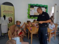 Policjant podczas spotkania z dziećmi w Mikołowie oś. Mickiewicza, opowiada o tym jak ważne jest noszenie odblaskowych elementów