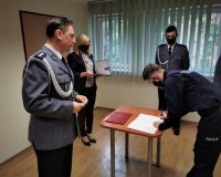 na zdjęciu: młody policjant podpisuje akt ślubowania, wszystko odbywa się w obecności komendanta oraz pracownika cywilnego, Mikołów, 30 września