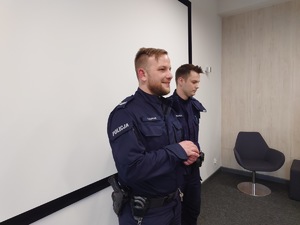 dwóch policjantów przemawia do uczestników spotkania