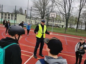 policjant drogówki rozmawia z uczniami, scena ma miejsce wna boisku szkolnym w Mikołowie