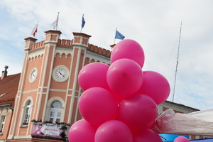 pęk różowych balonów, w tle ratusz miasta