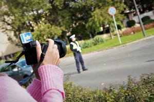 kobieta w różowym swetrze robi zdjęcie policjantowi drogówki