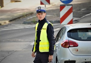 policjant drogówki w odblaskowej kamizelce w rejonie oznakowanego przejścia