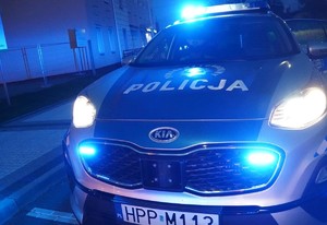 policyjny radiowóz kia z włączonymi niebieskimi światłami błyskowymi