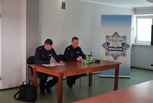 zdjęcie przedstawia dwóch policjantów siedzących przy stole