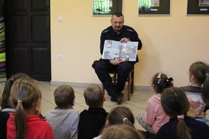 na zdjęciu widać policjanta z książką i dzieci